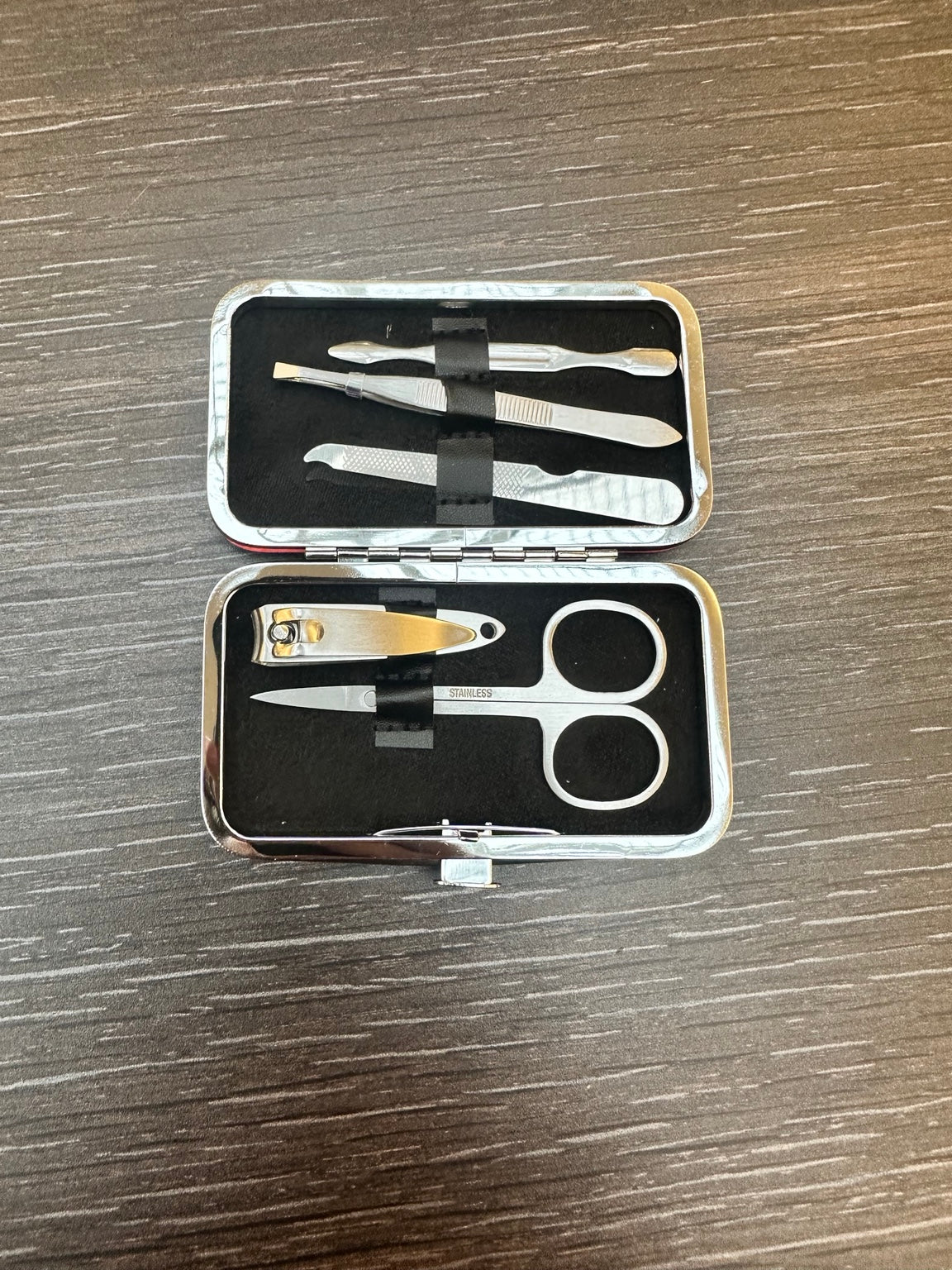 Kit de manucure ouvert avec ses cinq accessoires : coupe-ongles, ciseaux, pince à épiler, lime et outil à double embout